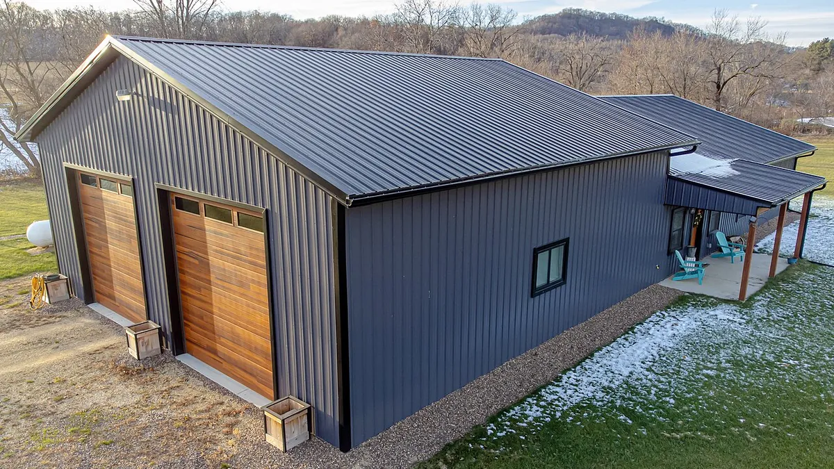 Design inspiration: raised view of a dark metal building with wood garage doors and a side canopy.