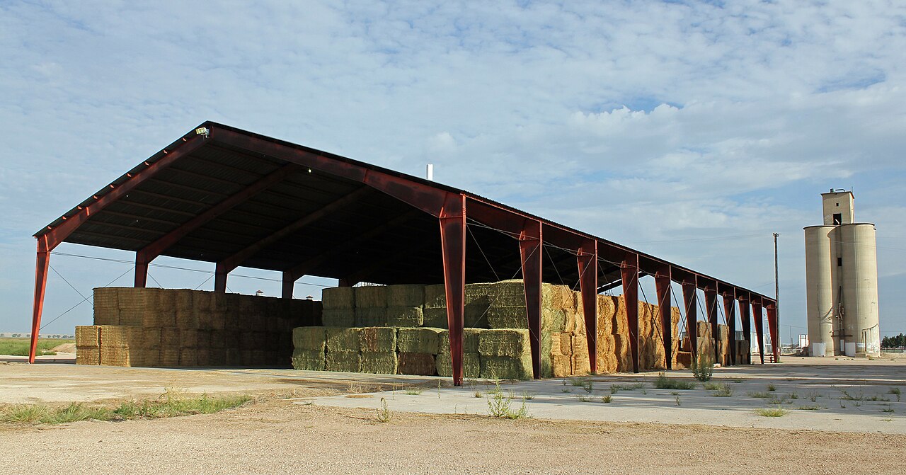 Design inspiration: open-sided hay storage barn with stacked bales and a nearby silo.