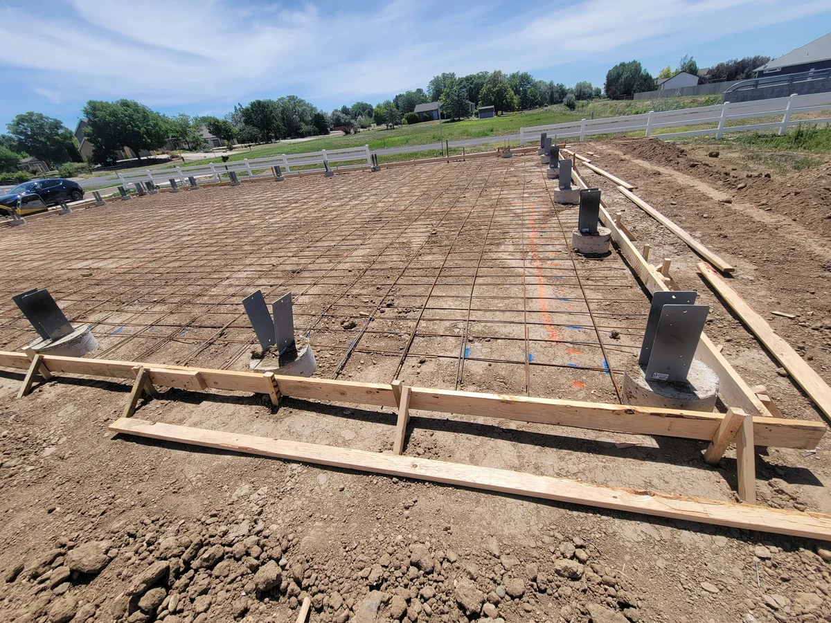 Rebar grid within timber slab formwork, with concrete piers and steel brackets, at the Colorado Springs project